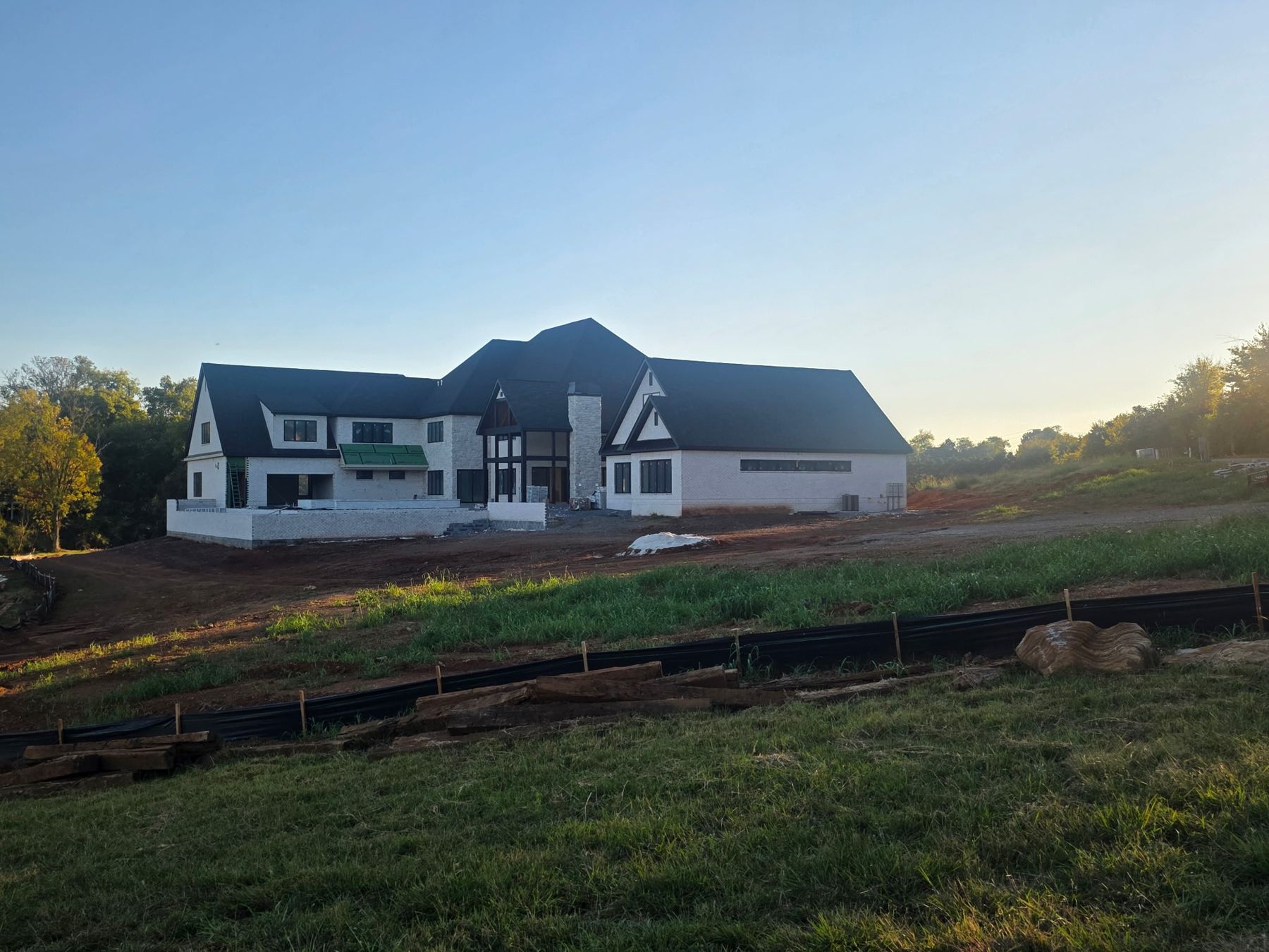Rear of the house with timber-framed great room windows and stone chimney