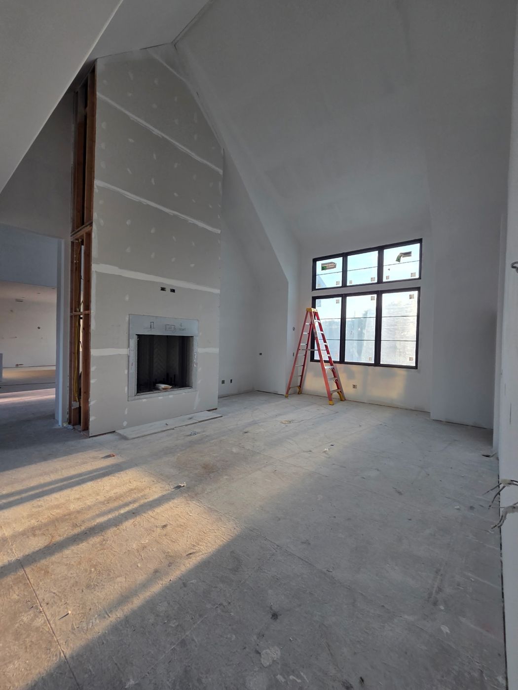Vaulted great room with full-height fireplace wall and tall windows