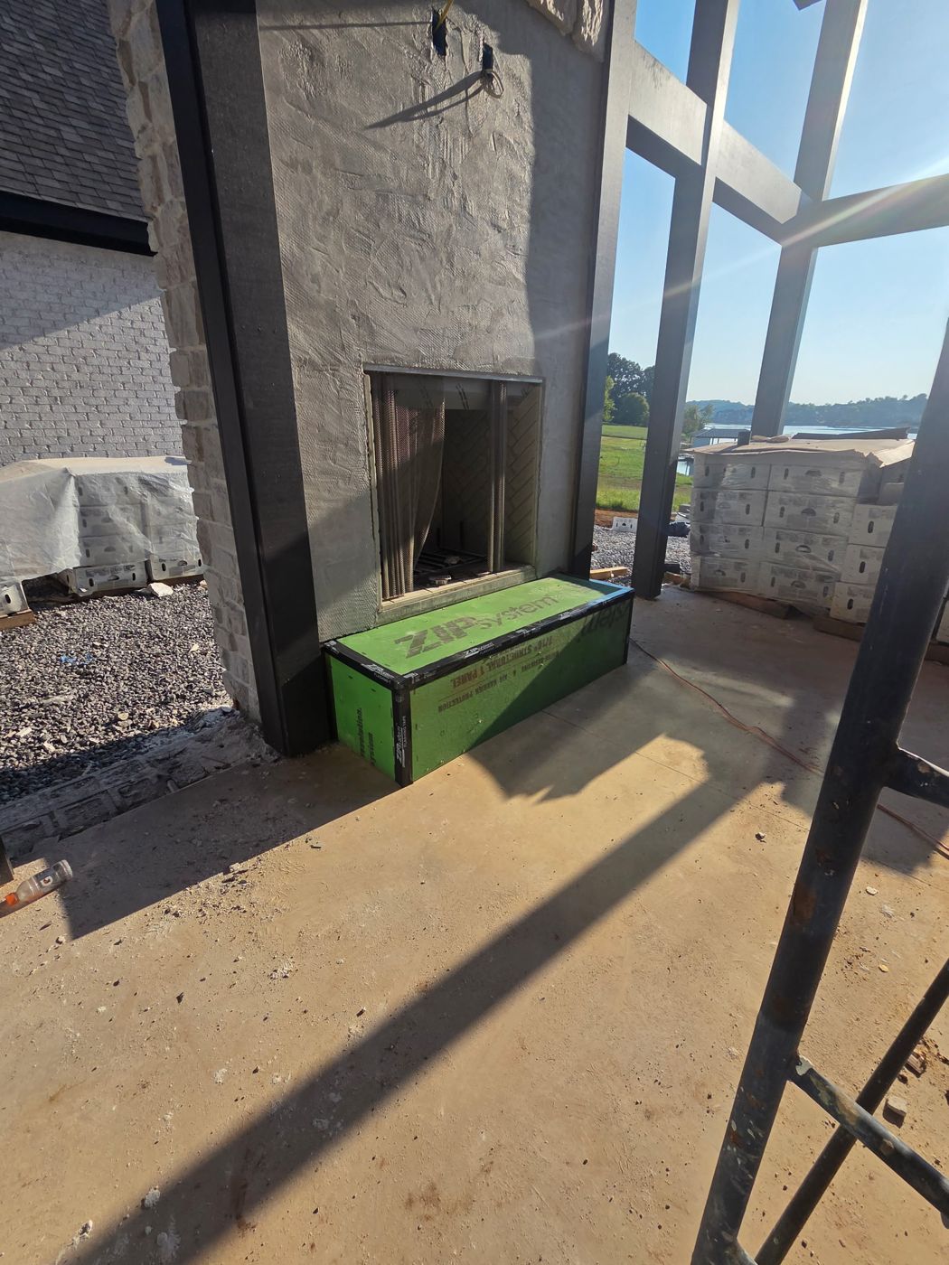 Covered porch fireplace with stone surround in progress and lake beyond