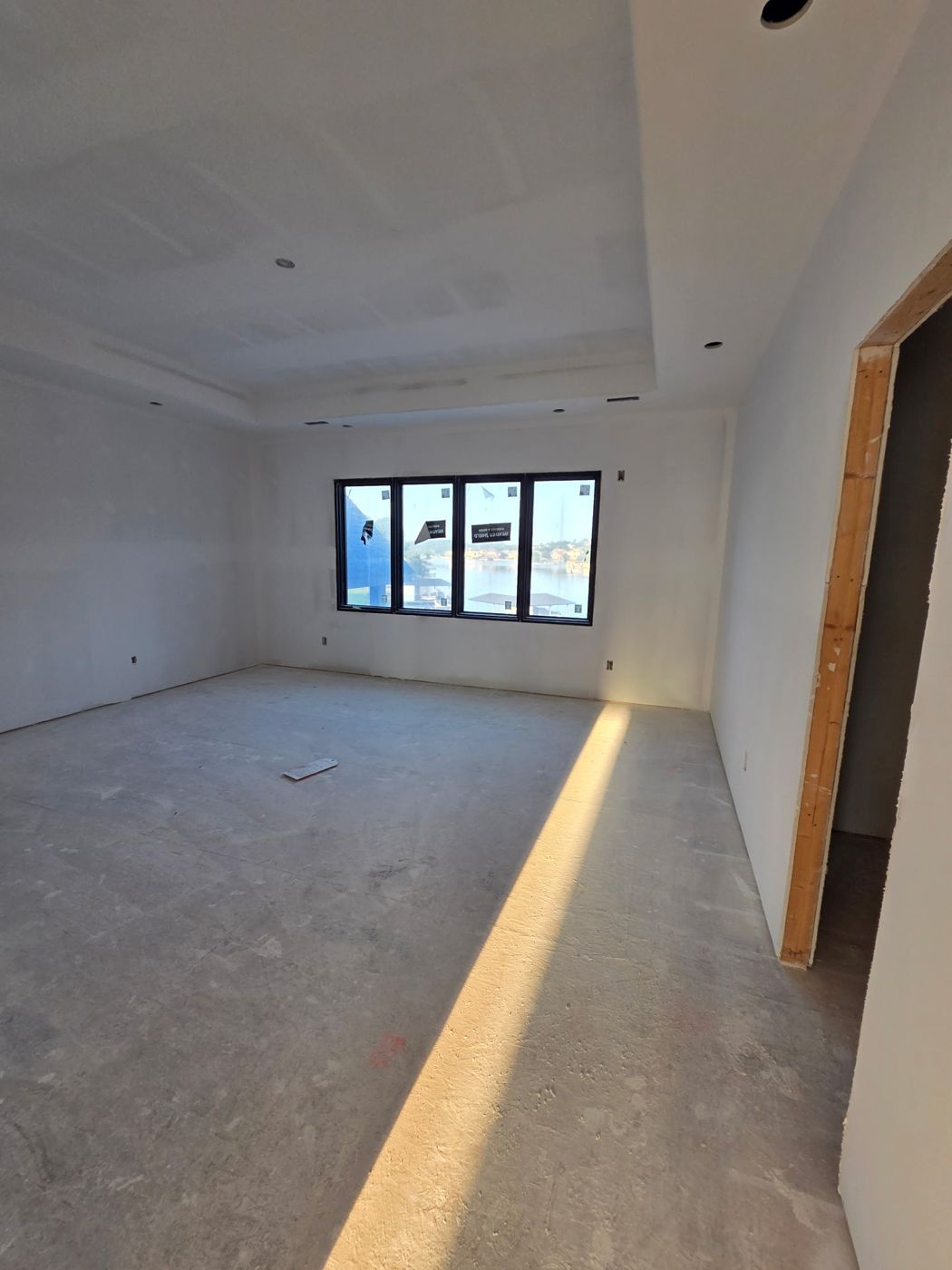 Primary suite with tray ceiling and four-panel window facing the lake